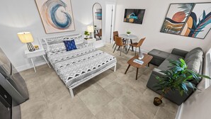 Une chambre moderne comprenant un lit, des tables de chevet, un bureau, un canapé et un téléviseur.