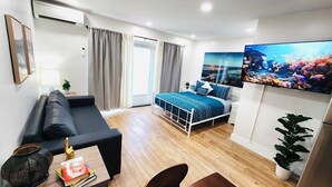 A modern bedroom with a bed, a sofa, a desk, and a TV.