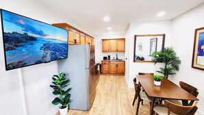 A modern kitchen with wooden cabinets, a stainless steel refrigerator, and a dining area with a wooden table and chairs.