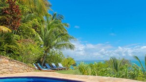 A swimming pool with lounge chairs and a view of the ocean. - Pousada Colibri (Cairu)