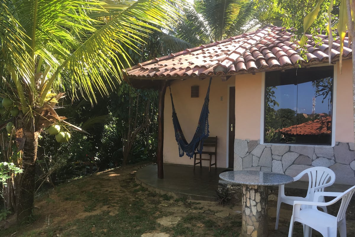 Un petit patio extérieur avec un mur en pierre, un hamac et une table avec des chaises.