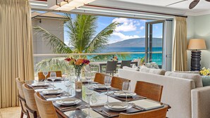 Un coin repas avec vue sur l’océan, un balcon avec un canapé et une grande fenêtre avec des rideaux.