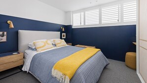 A bedroom with a bed, bedside tables, a lamp, and a window with blinds. - THE LITTLE BEACHSIDE APARTMENT  (Manly)