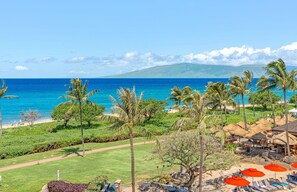Un complexe hôtelier tropical avec vue sur la plage, des chaises longues et une structure dotée d’un toit de chaume.