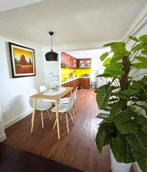Enjoy a spacious living area with a dining table, comfortable seating, and a beautiful potted plant.