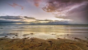 A beach with wet sand and a cloudy sky.