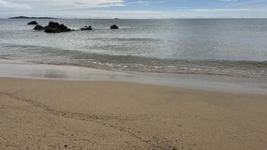 A beach with calm waters, a sandy shore, and distant islands. - Unique house in an idyllic situation on a beach (Port Ellen, Isle of Islay)