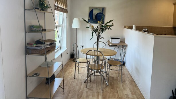 Una cocina compacta con comedor, que incluye una mesa redonda, sillas, una lámpara y una pequeña planta en maceta.