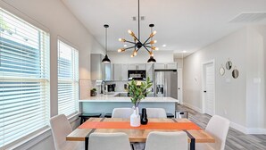 Een moderne keuken met witte kasten, een centraal eiland en een roestvrijstalen koelkast.