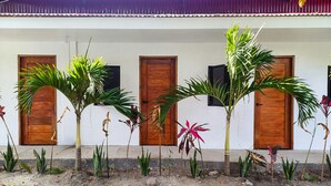Un bâtiment doté de trois portes en bois et d’une rangée de plantes en pot devant l’entrée.