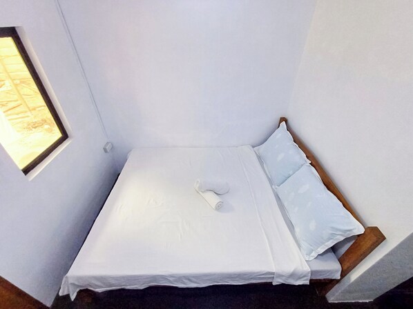 A small, single-bed room with white bedding, a wooden headboard, and a small window. - Isla Linaw Siargao (General Luna)