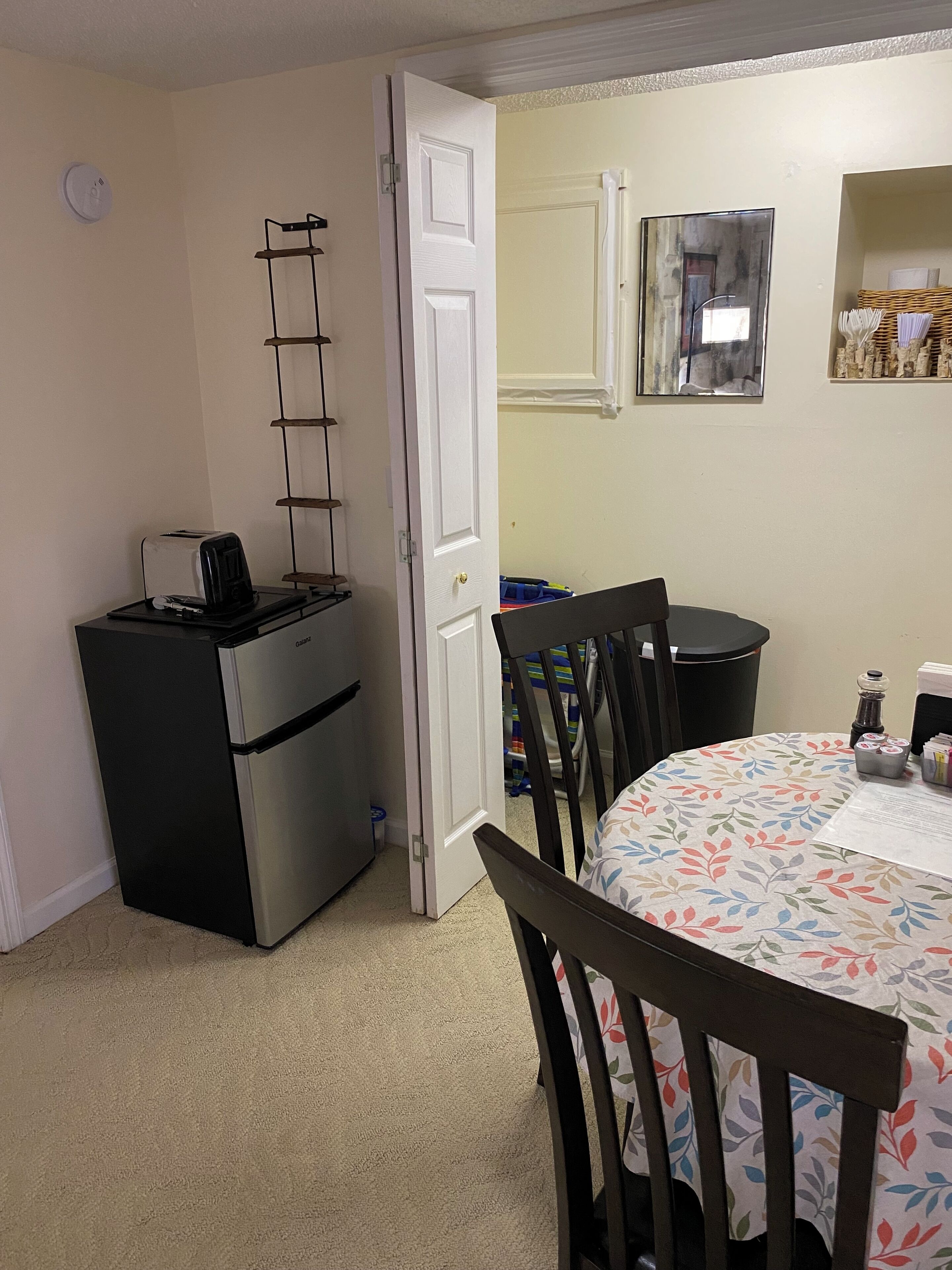 A compact kitchen with a refrigerator, a toaster, and a small dining table with chairs.