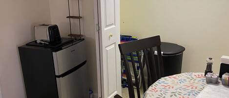 A compact kitchen with a refrigerator, a toaster, and a small dining table with chairs.
