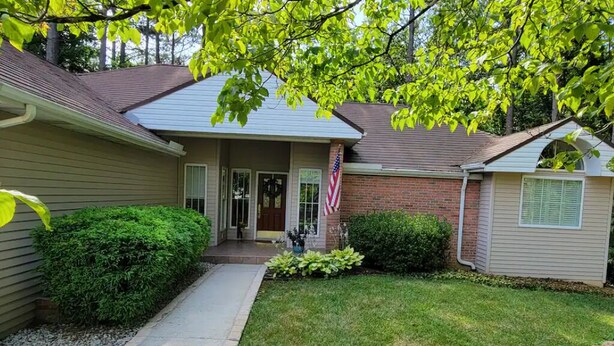 A two-story house with a front porch, a small garden, and an American flag. - Central Tellico Village Private Apartment, Experience peace & quiet, Non-smoking (Loudon)