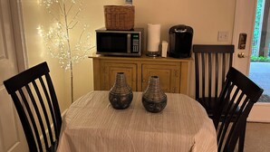 A dining area with a table set for two, a microwave, a coffee maker, and decorative items. - Central Tellico Village Private Apartment, Experience peace & quiet, Non-smoking (Loudon)