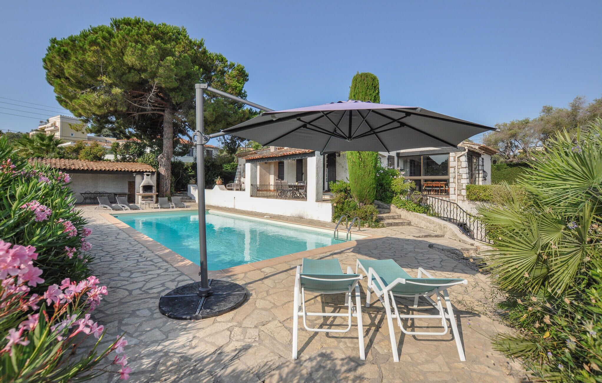 A swimming pool with lounge chairs and a covered area.