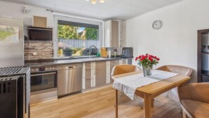 Une cuisine moderne avec un mur de crédence en pierre, des appareils électroménagers en acier inoxydable et une fenêtre donnant sur un jardin.