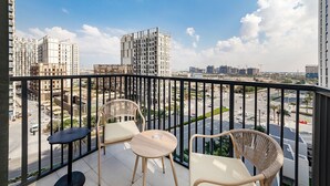 A balcony with wicker chairs and a small round table, overlooking a cityscape with modern buildings and a clear sky. -  Premium Apartments at Executive Residences (Dubai)