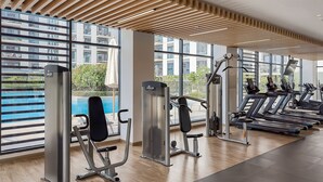 A modern gym with exercise equipment, large windows, and a wooden ceiling design. -  Premium Apartments at Executive Residences (Dubai)