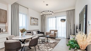 A modern living room with a dining area, featuring a sofa, armchairs, a coffee table, and a rug. -  Premium Apartments at Executive Residences (Dubai)
