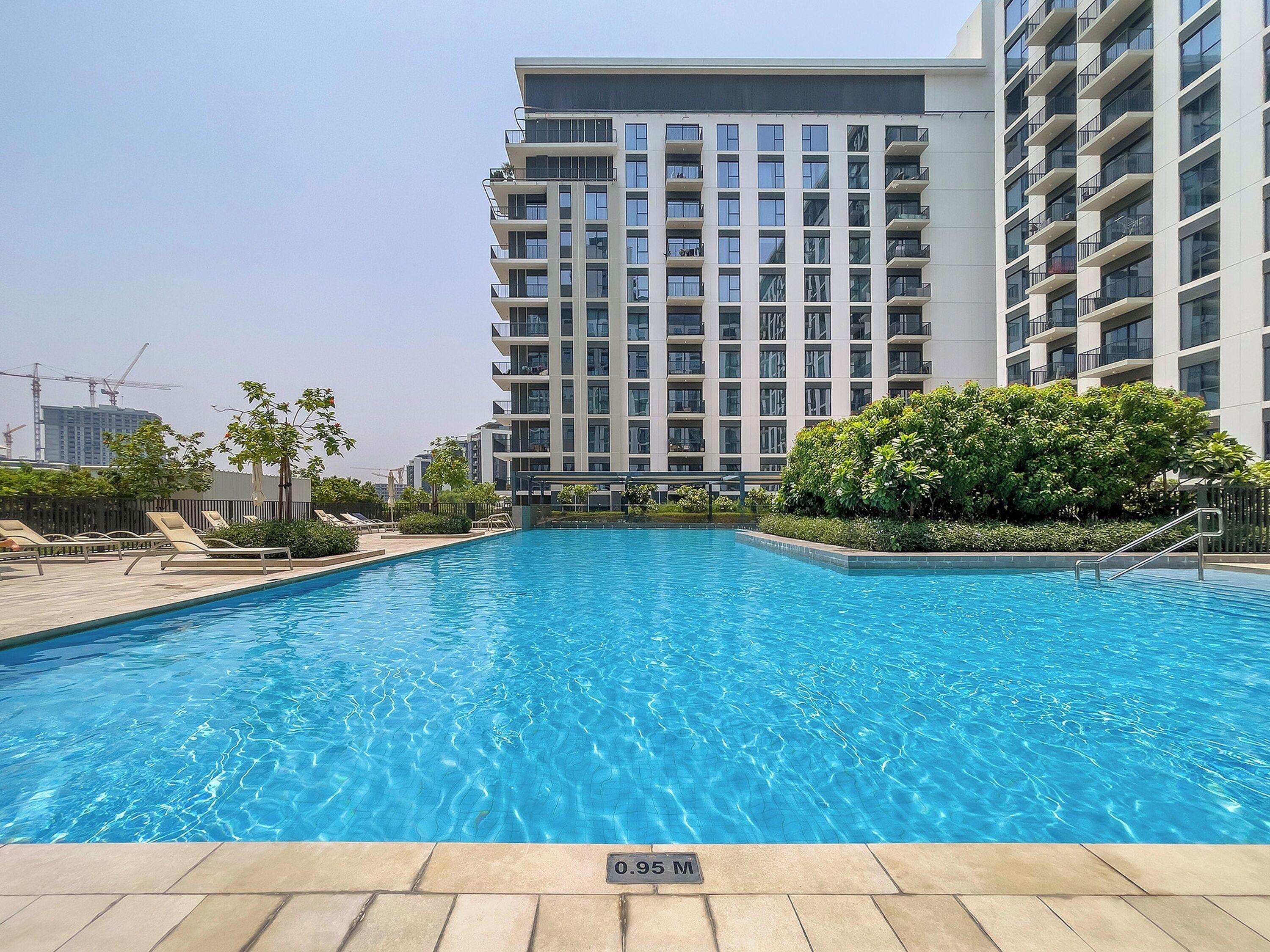 A swimming pool surrounded by a modern apartment building with multiple balconies.