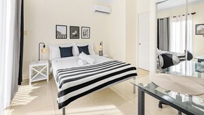 A modern hotel room with a large bed, a bedside table with a lamp, a mirror, and a view of the city through the window. - Lovely tiny home at Sunnybank CBD Street Parking (Sunnybank)