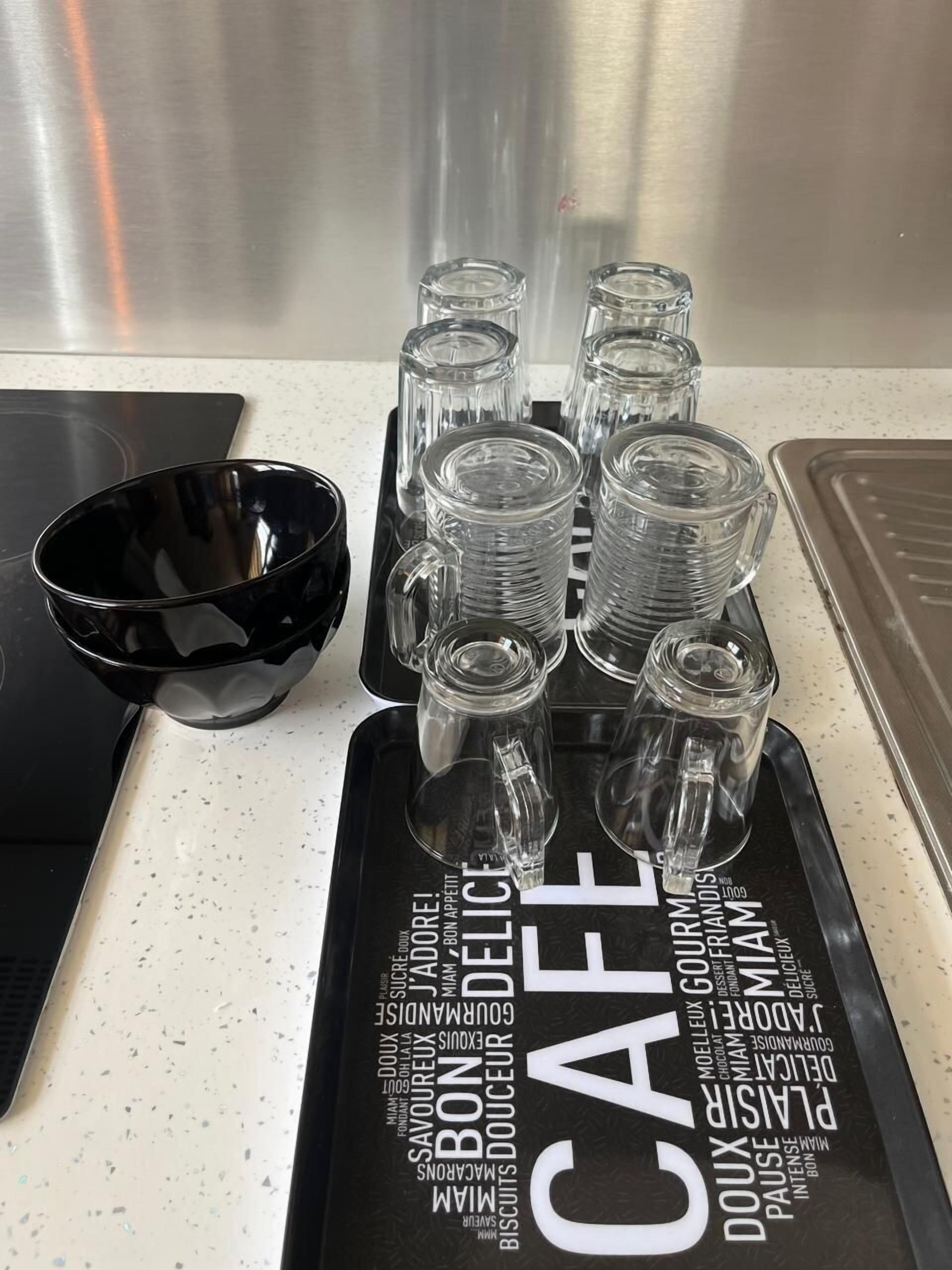 Un comptoir de cuisine sur lequel se trouve un plateau noir contenant des verres en verre transparent et un bol noir.