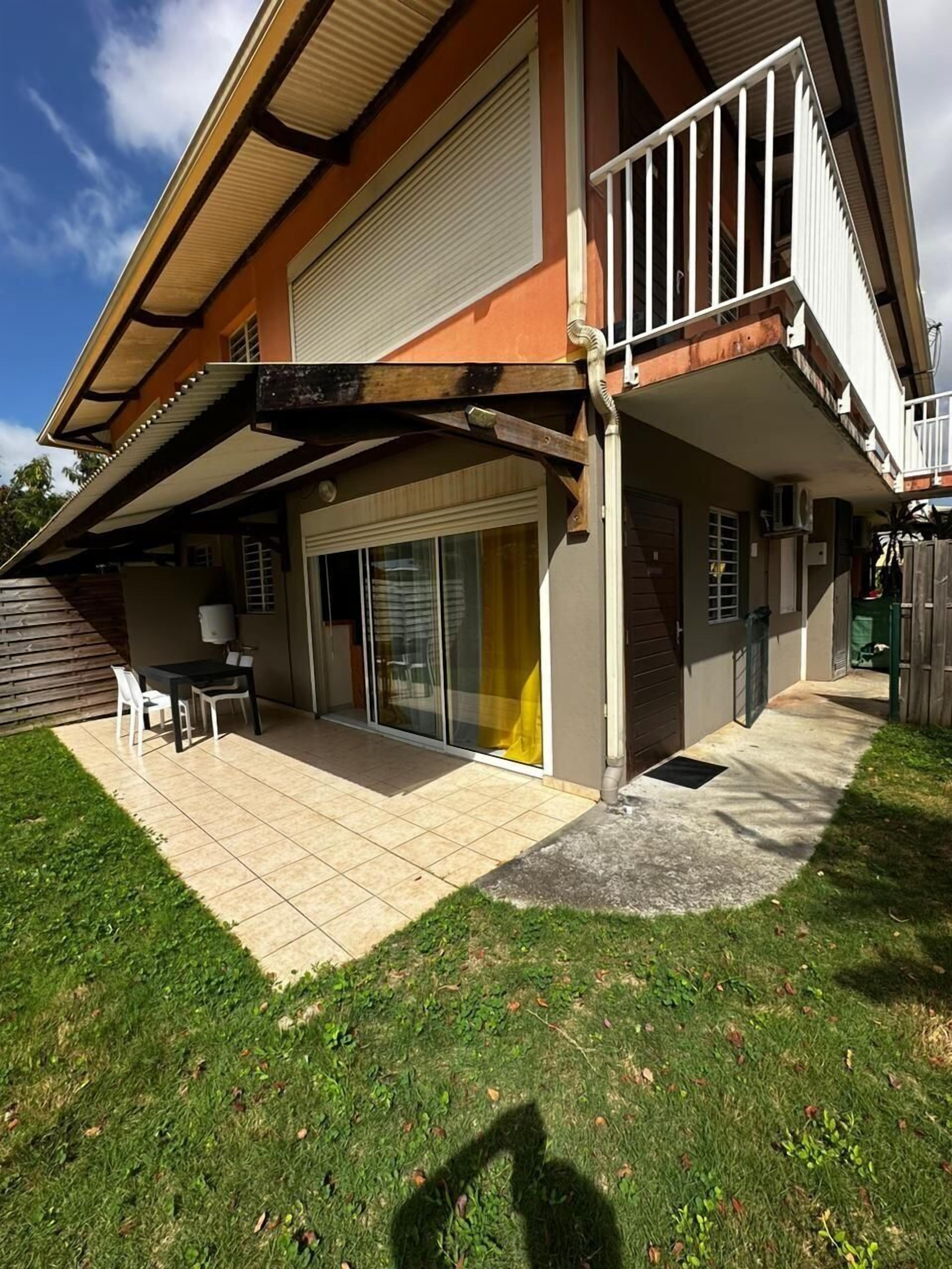 A two-story house with a covered patio, a sliding glass door, and a small outdoor seating area.