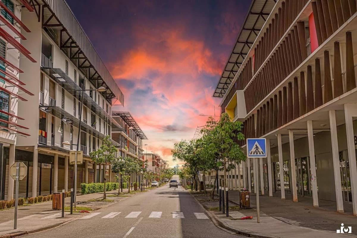A street with modern buildings, a pedestrian crossing sign, and a clear sky.