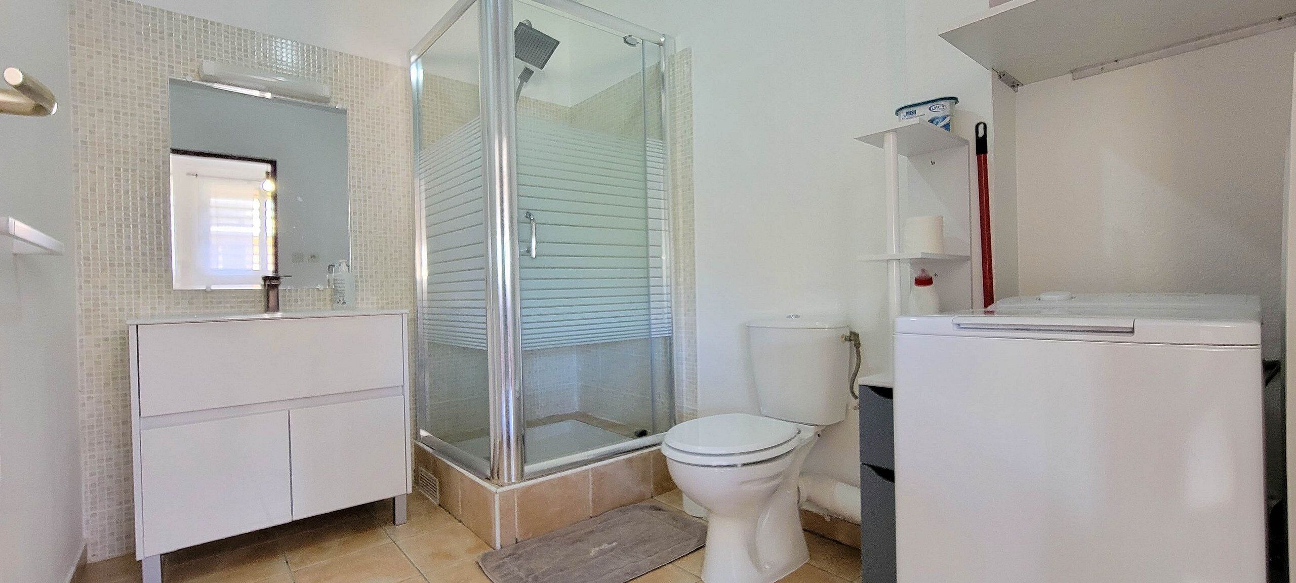 A bathroom with a glass-enclosed shower, a toilet, and a white cabinet.