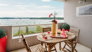 A balcony with a wooden table, chairs, a small plant, and a view of boats on the water. - Terrasses d'Emeraude by Interhome (Dinard)