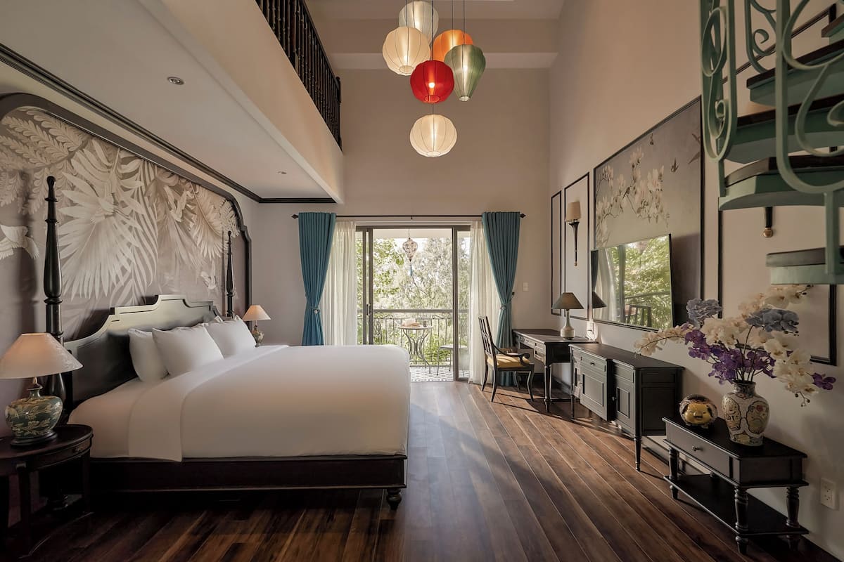 Un dormitorio con una cama grande, un escritorio y un balcón con cortinas.