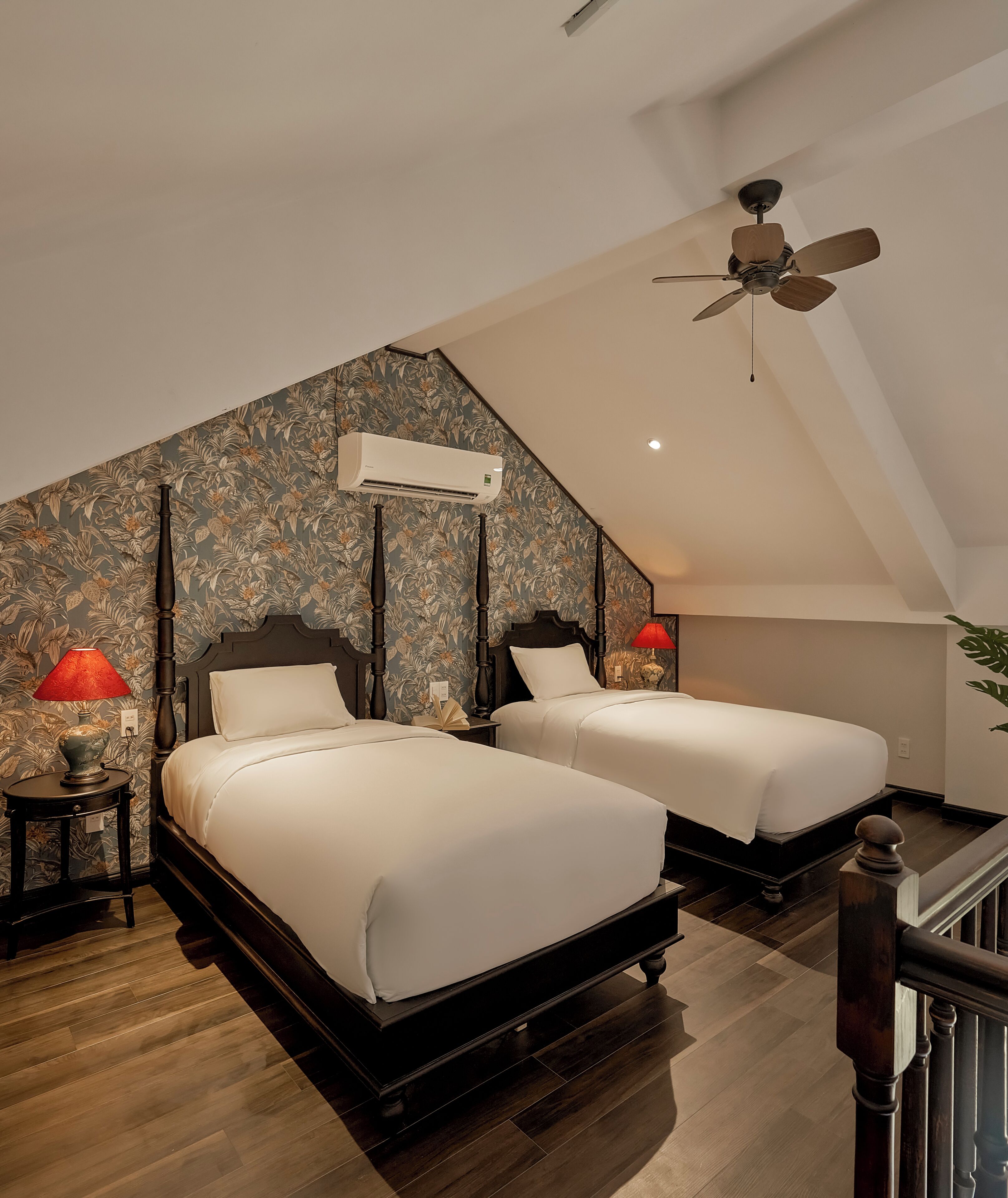 A bedroom with two beds, a ceiling fan, and a decorative wall.