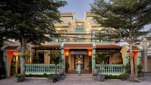 Un hotel boutique dallo stile architettonico tradizionale, con un ingresso centrale caratterizzato da un tetto in tegole e ringhiere decorative.