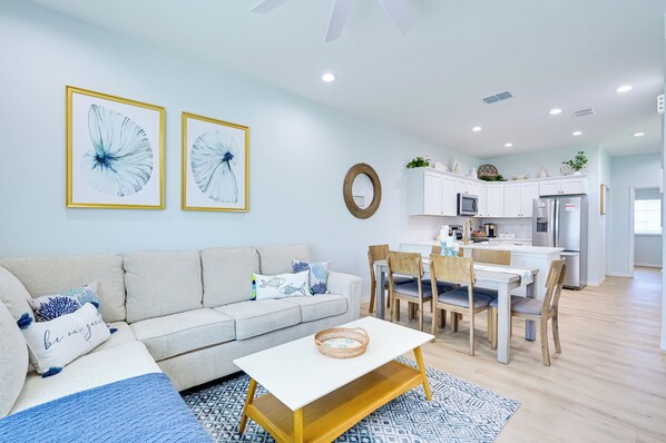 Uma sala de estar moderna com sofá, mesa de centro e área de jantar.