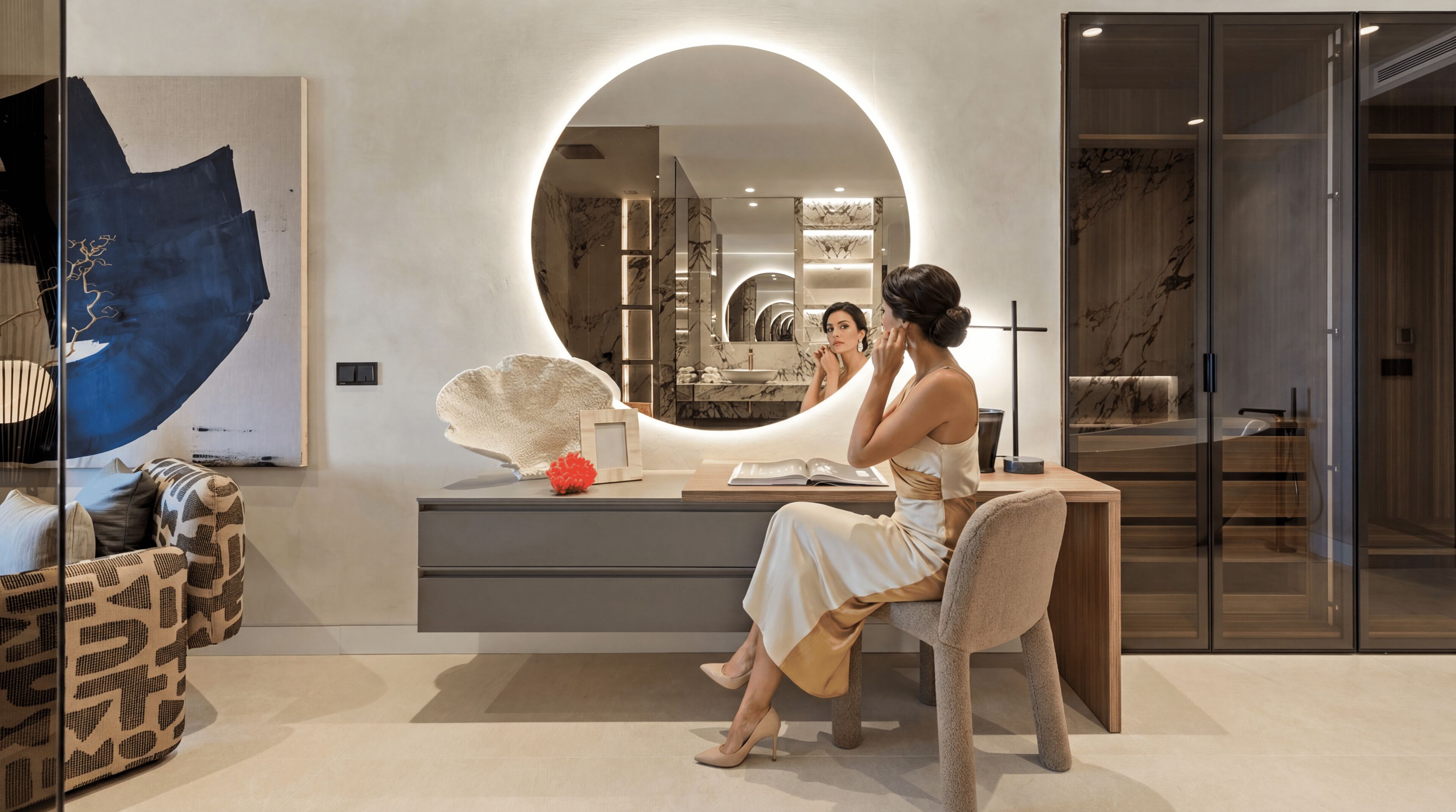A modern bathroom with a vanity, a large mirror, and a seating area.