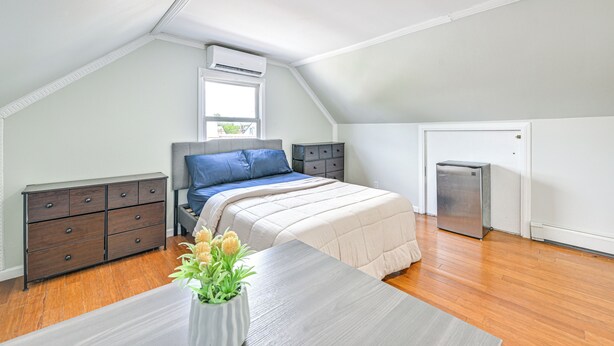 Un dormitorio con cama, cómoda y un refrigerador pequeño.