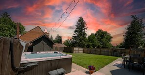 Un jardin avec un jacuzzi, un abri en bois, une pelouse et une clôture en bois.