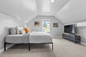 A bedroom with a bed, a TV, and a window.