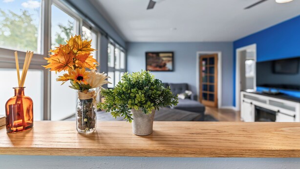 A modern kitchen with a wooden countertop, a ceiling fan, and a view of the living area through large windows. - "Bright and Stylish Anchorage 2 - Bedroom House - "7 mins from ANC" (Anchorage)
