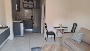 Una sala de estar con un sofá, una mesa de centro y un comedor con una mesita y sillas.