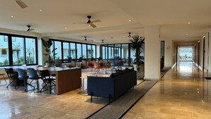 Un hall de hotel espacioso y moderno con una zona de estar central, amplias ventanas que ofrecen vistas al exterior y un suelo limpio y pulido.