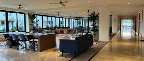 A spacious, modern hotel lobby with a central seating area, large windows offering views of the outdoors, and a clean, polished floor.