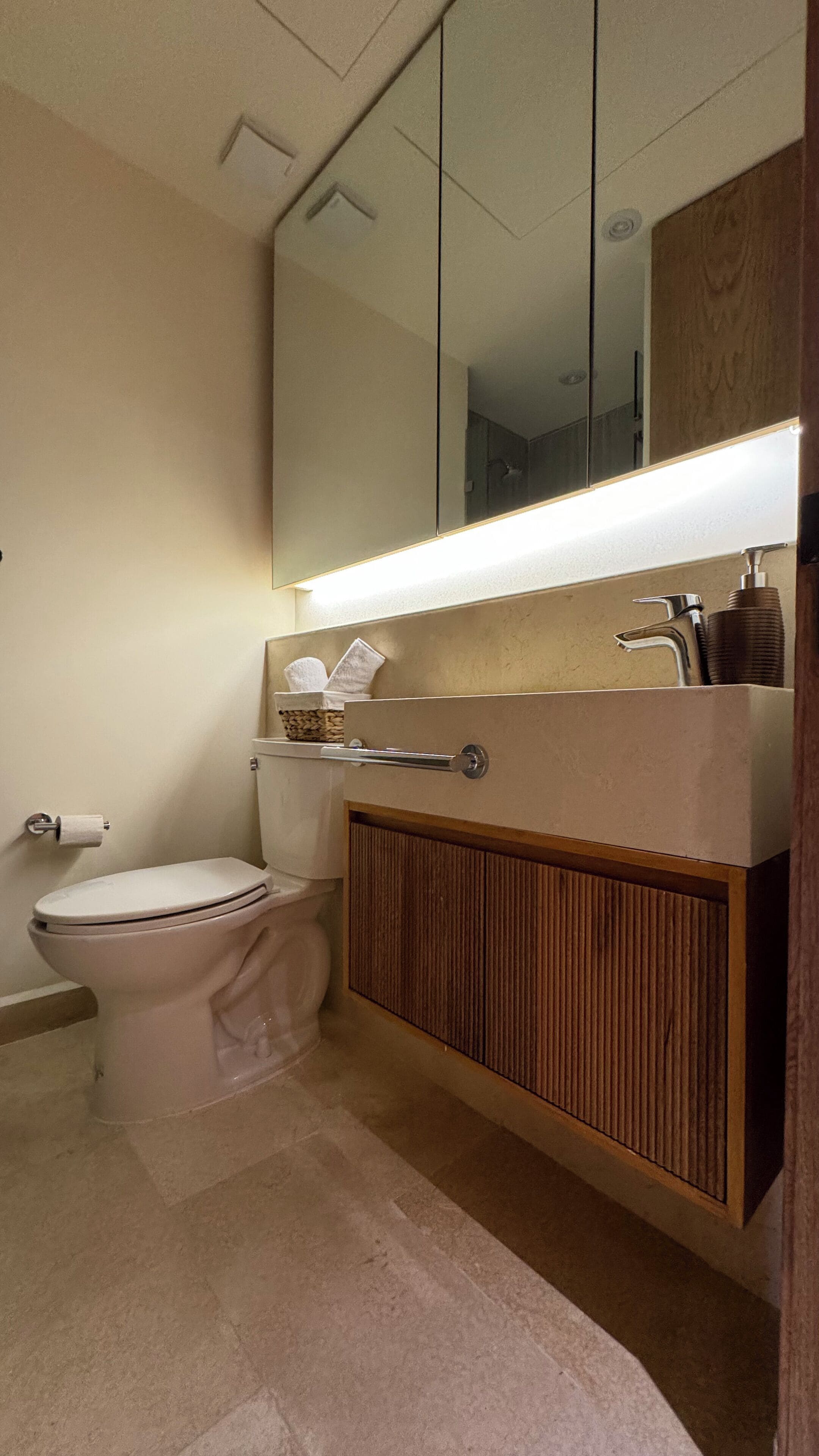 A bathroom with a toilet, a sink with a mirror above it, and a towel rack.