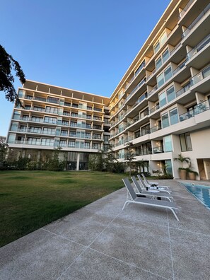 Ein mehrstöckiges Hotel mit Schwimmbad, Außenbereich und gepflegter Rasenfläche.