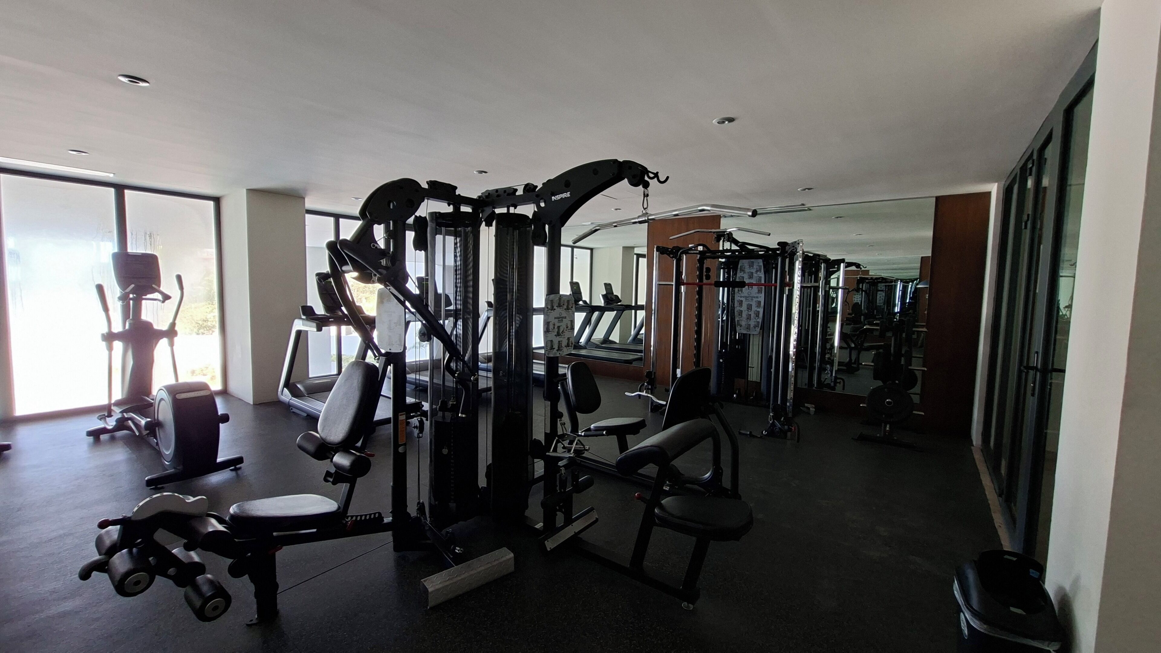 A gym with various exercise machines, a treadmill, and a weight rack.
