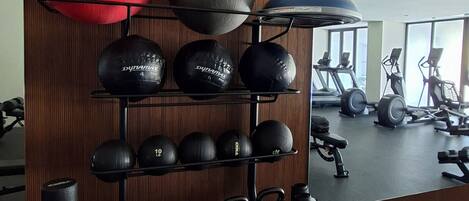 A gym with exercise equipment, including kettlebells, medicine balls, and a treadmill.