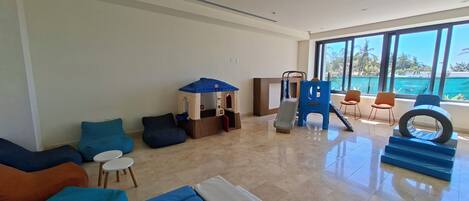 A spacious living area with a play structure, comfortable seating, and large windows offering a view of the outdoors.