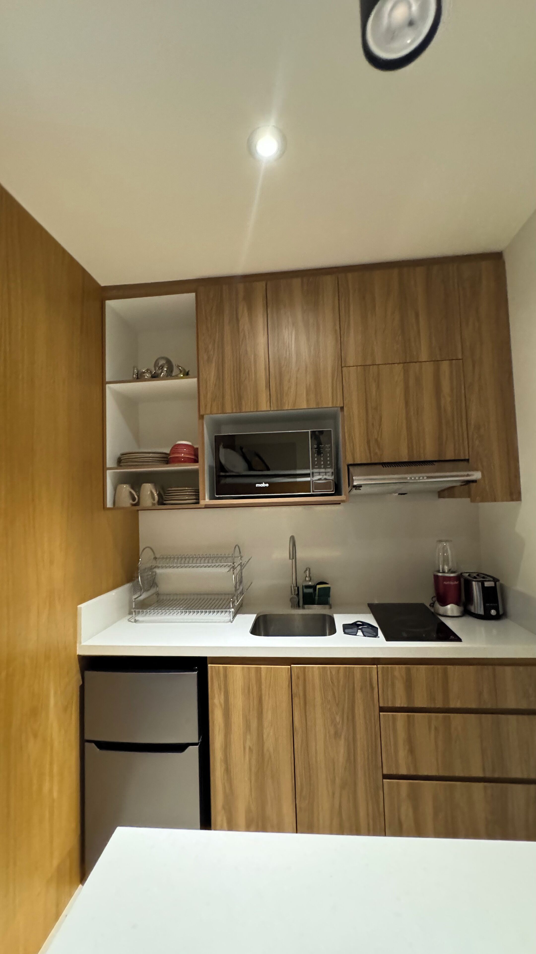 A compact kitchen with wooden cabinets, a built-in microwave, a sink, and a small countertop area.