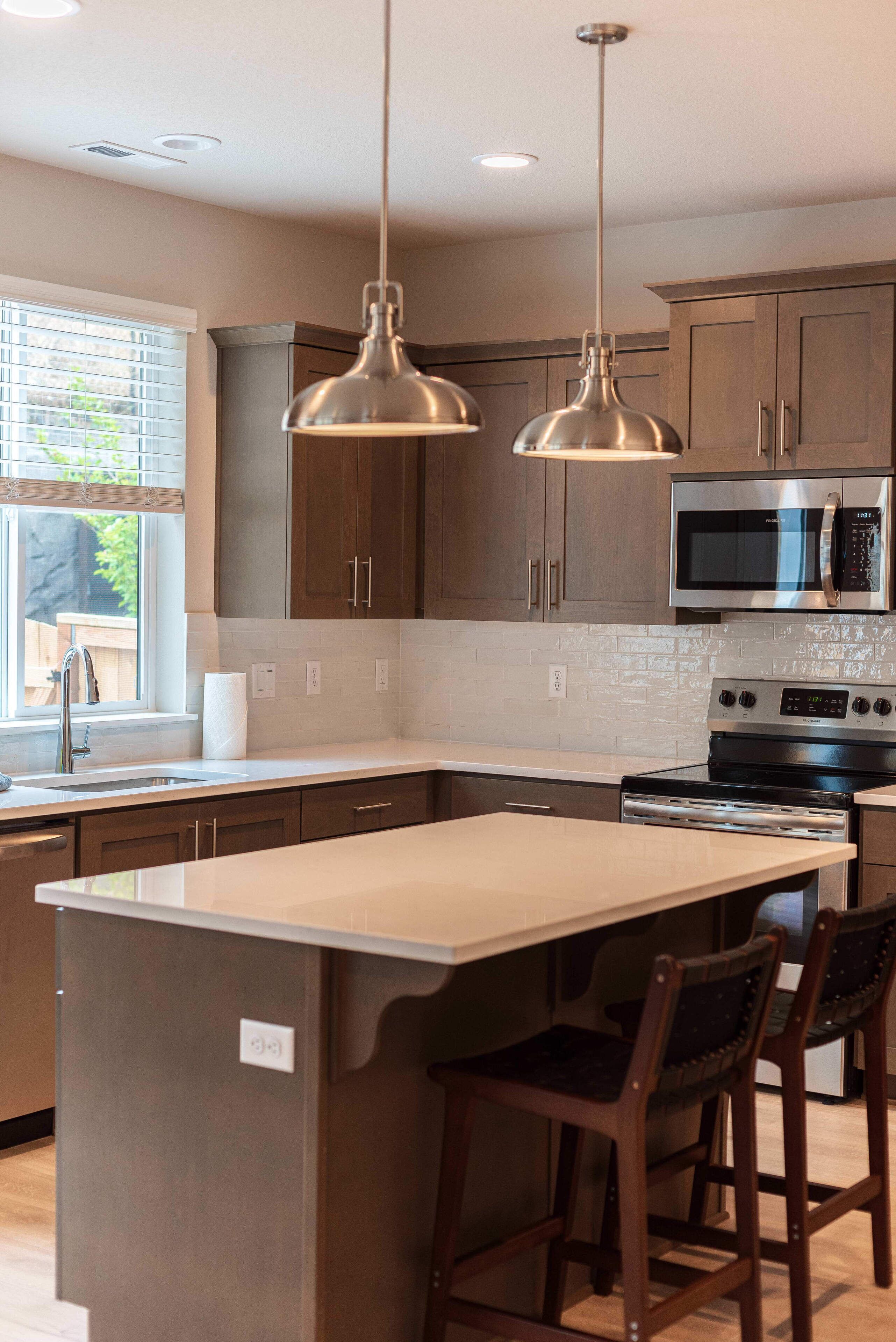 A modern kitchen with a central island, stainless steel appliances, and pendant lighting.